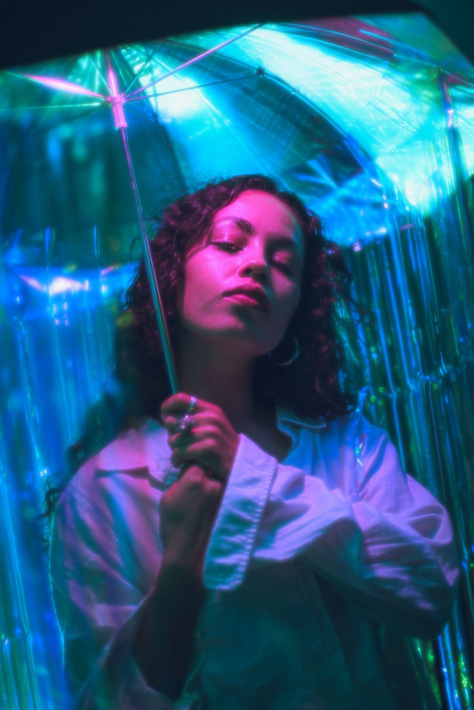 Mulher sob um guarda-sol iluminado em neon ciano e magenta